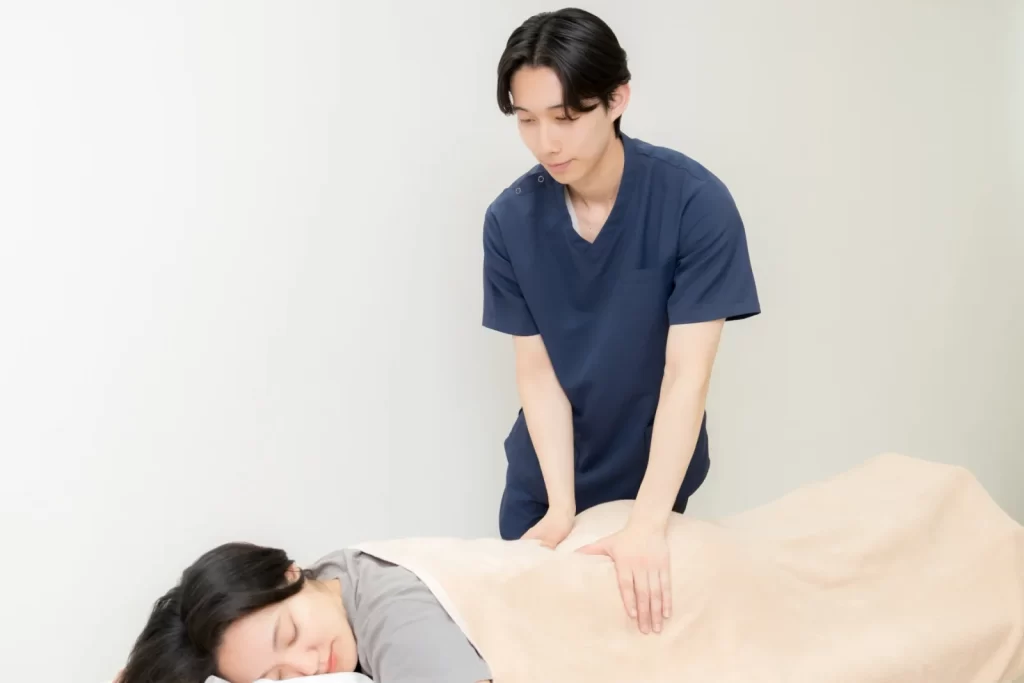 施術者が利用者の背中に手を当てて施術する様子