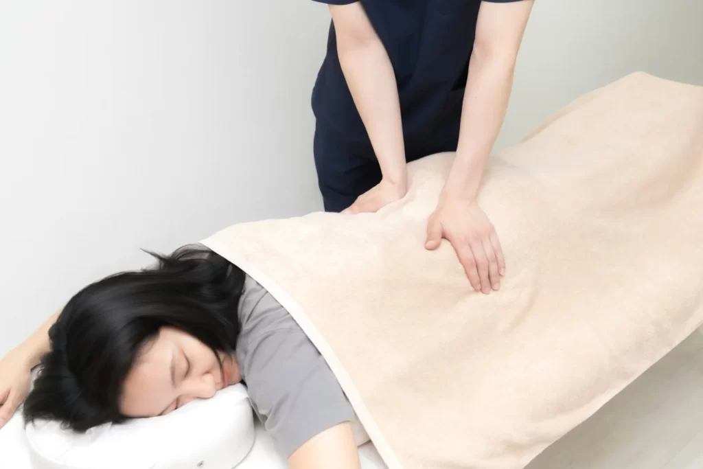 施術者が利用者の腰まわりに手を当てて施術する様子