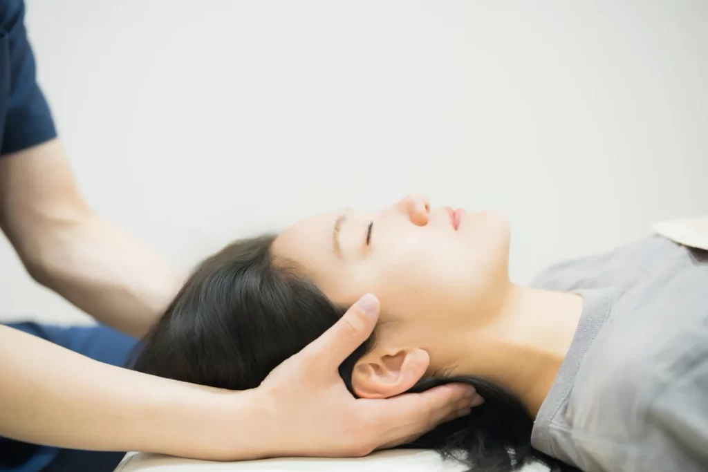 施術者が利用者の首まわりに手を添えて状態を確認する様子