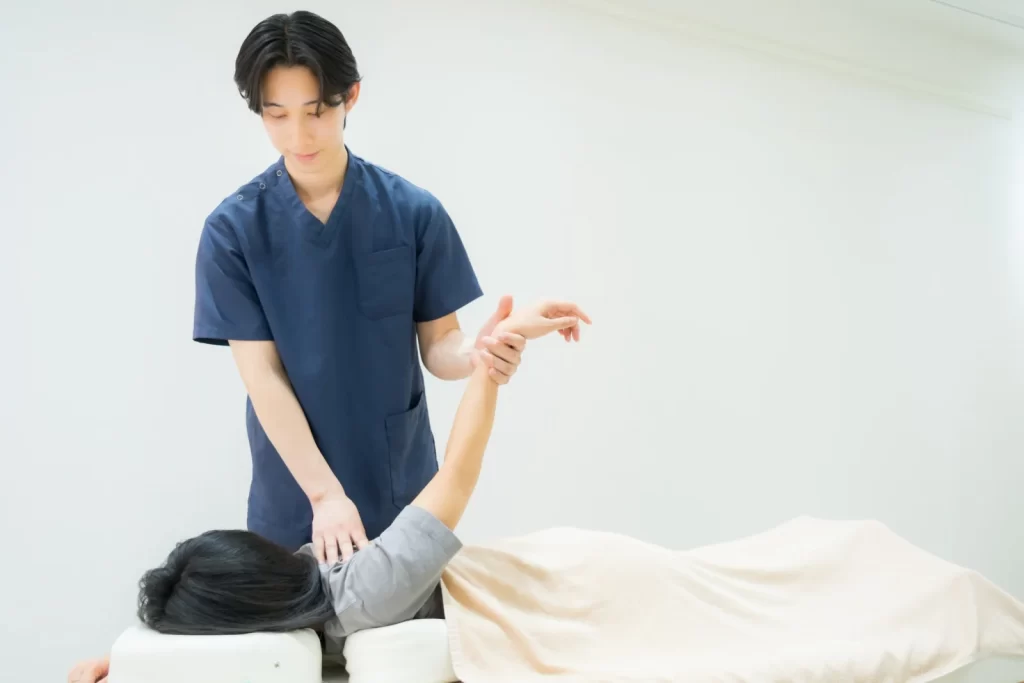 施術者が利用者の腕を支えて肩まわりの動きを確認する様子
