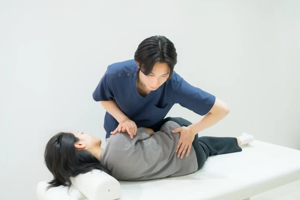 施術者が横向きの利用者の腰まわりに手を添える様子